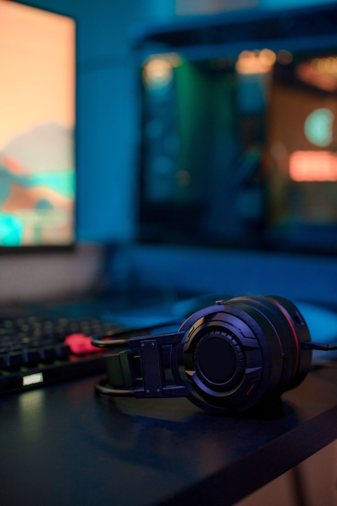 Gaming headphones beside a desktop computer setup.